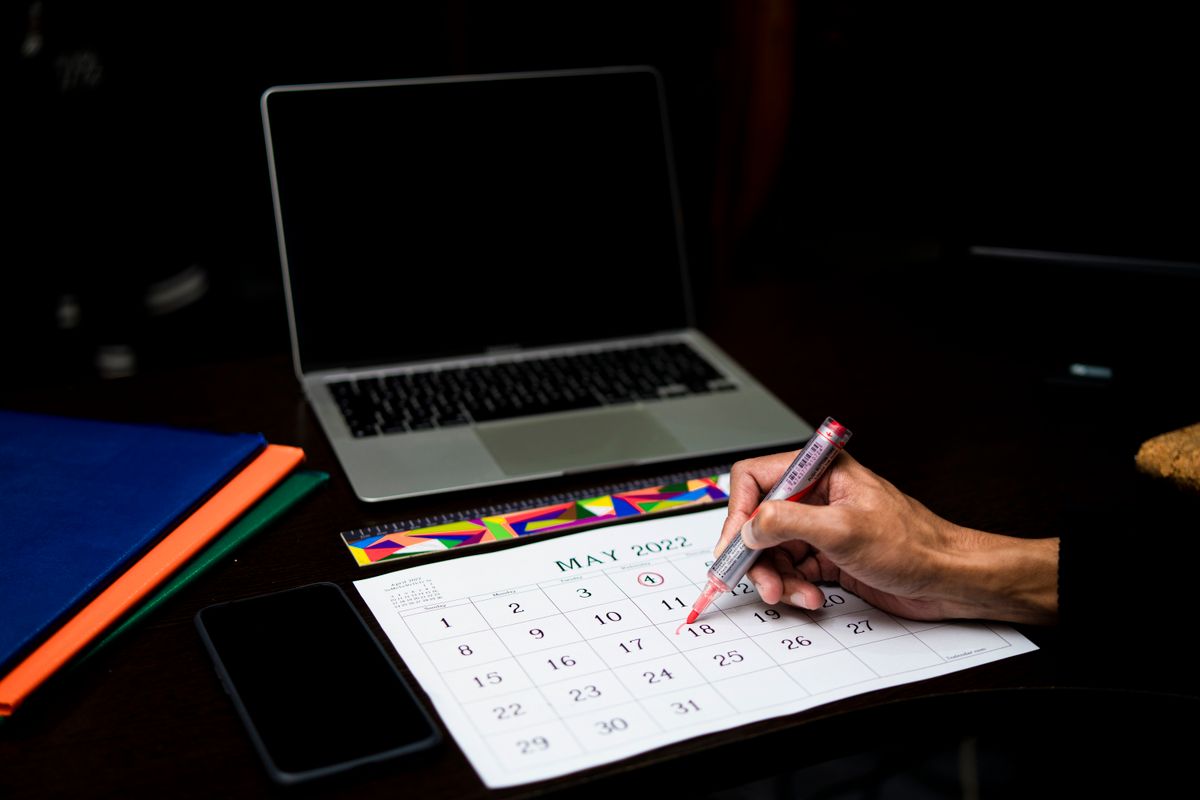 A calendar beside a laptop, illustrating travel planning
